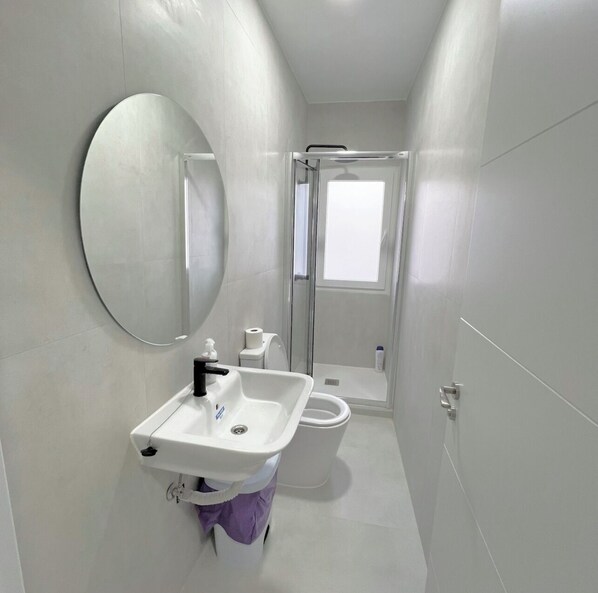 A compact bathroom with a white sink, toilet, and shower. - Hostel Vallecas (Madrid)