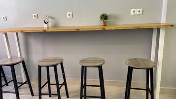 Una zona de bar con un mostrador de madera y tres taburetes negros.