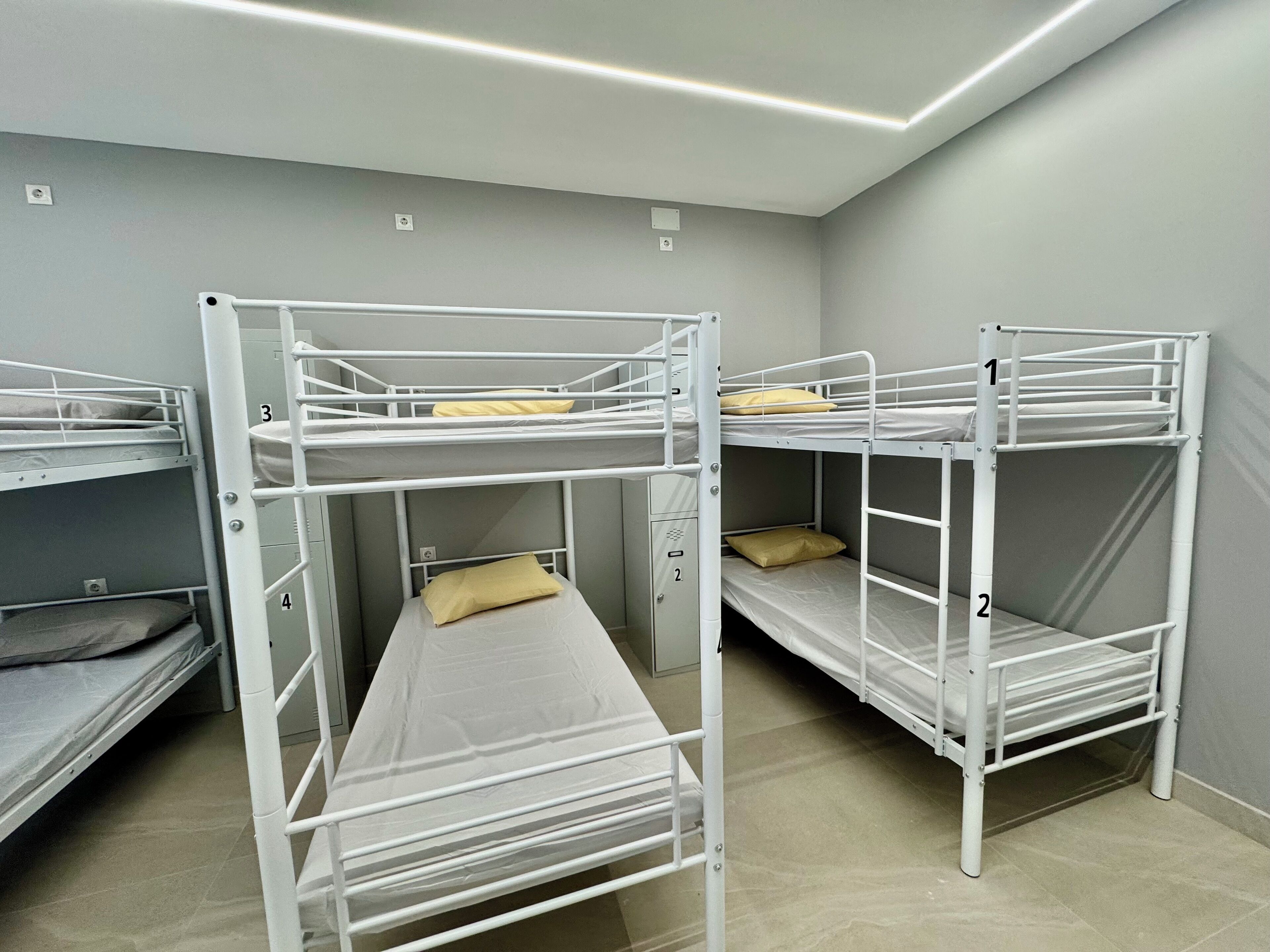 A room with bunk beds, each labeled with numbers 1 to 4, and a small cabinet below the beds.