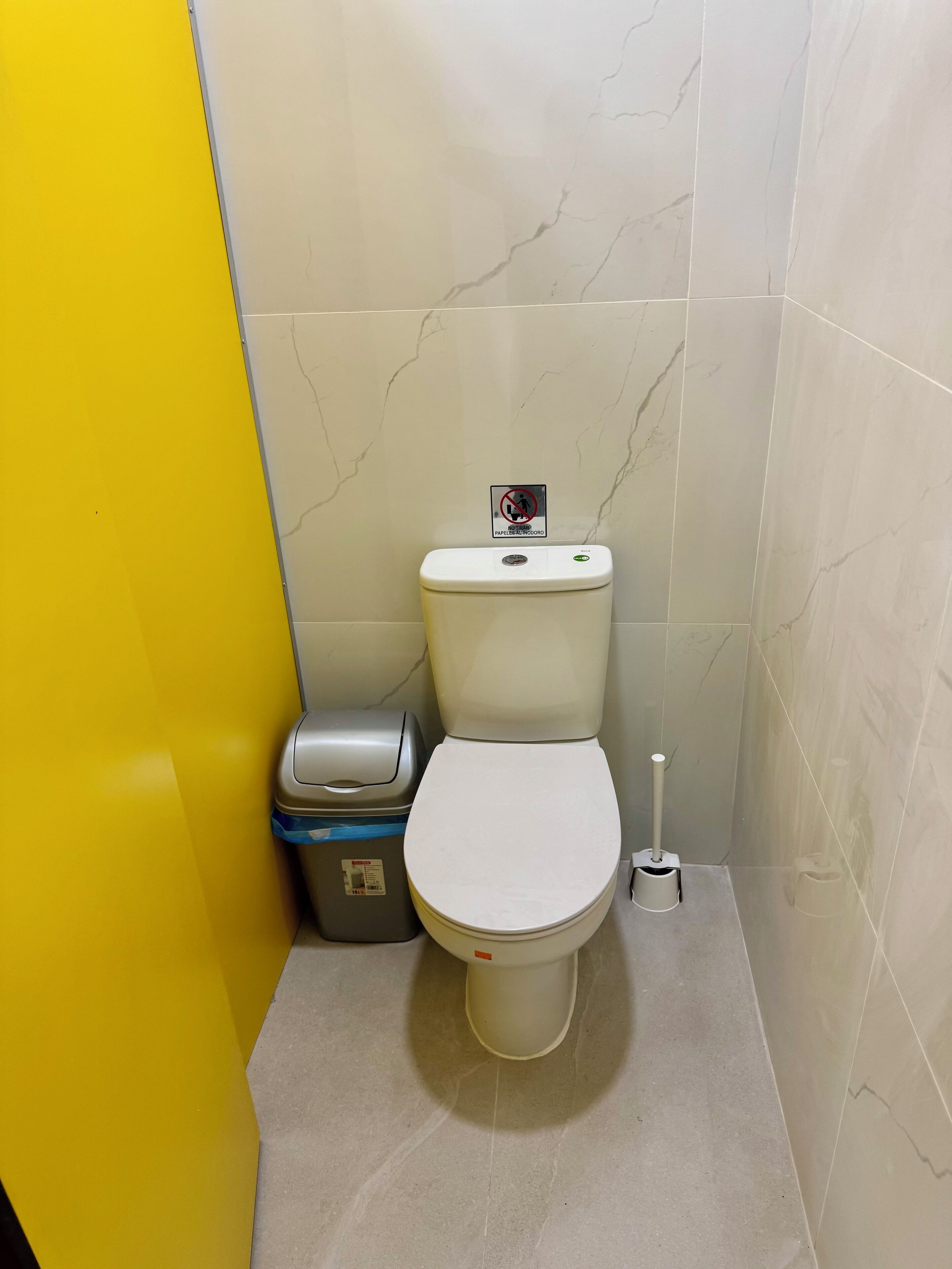 A bathroom with a toilet, a trash bin, and a bidet.