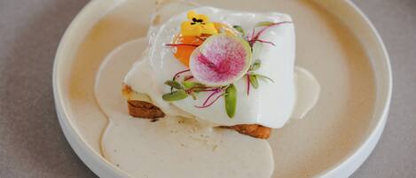 A plate with a poached egg, a slice of orange, and some greens.