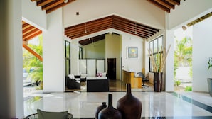 A spacious lobby with a high ceiling, a reception desk, and a seating area with a sofa and chairs. - Portofino Hotel & Restaurante (Barra de Potosi)