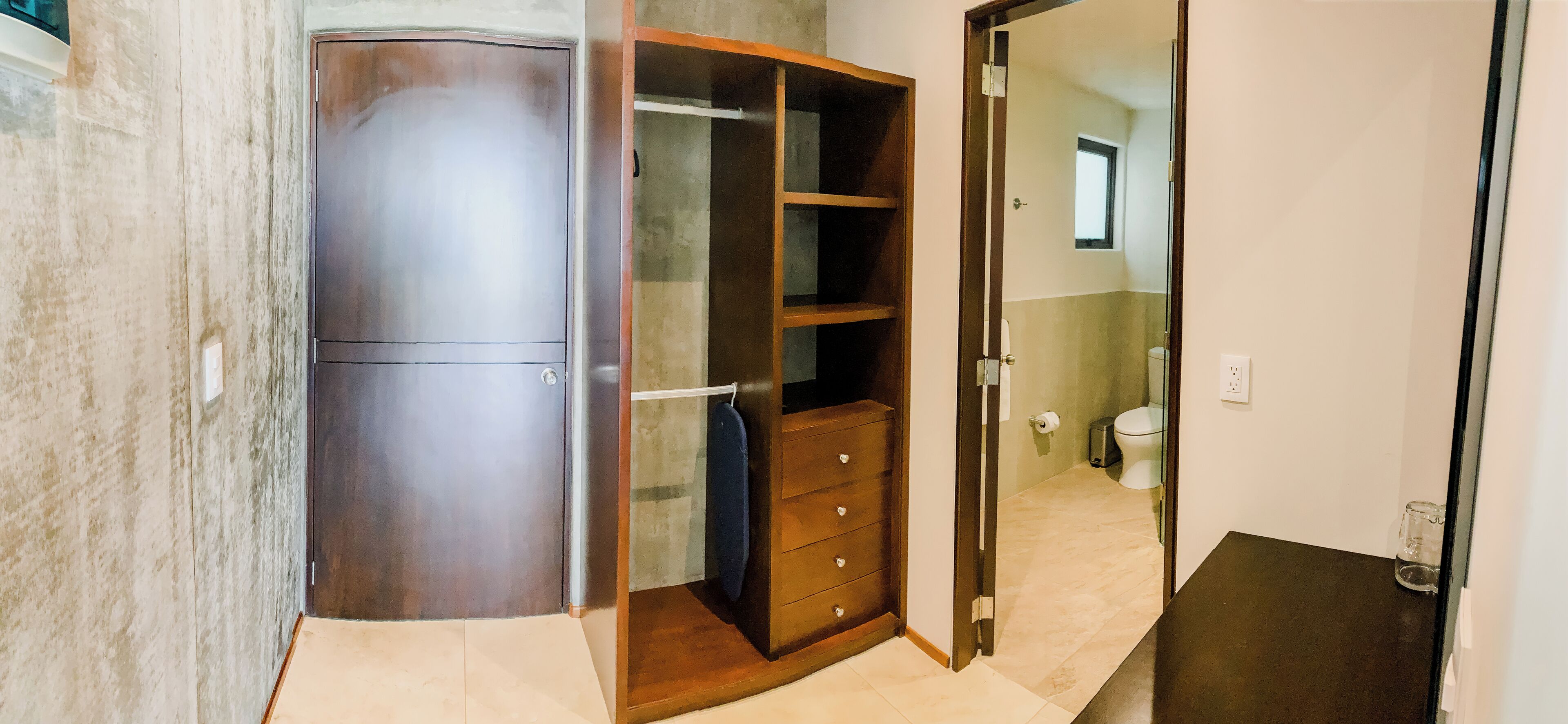 A room with a wardrobe, a mirror, and a toilet visible through an open door.
