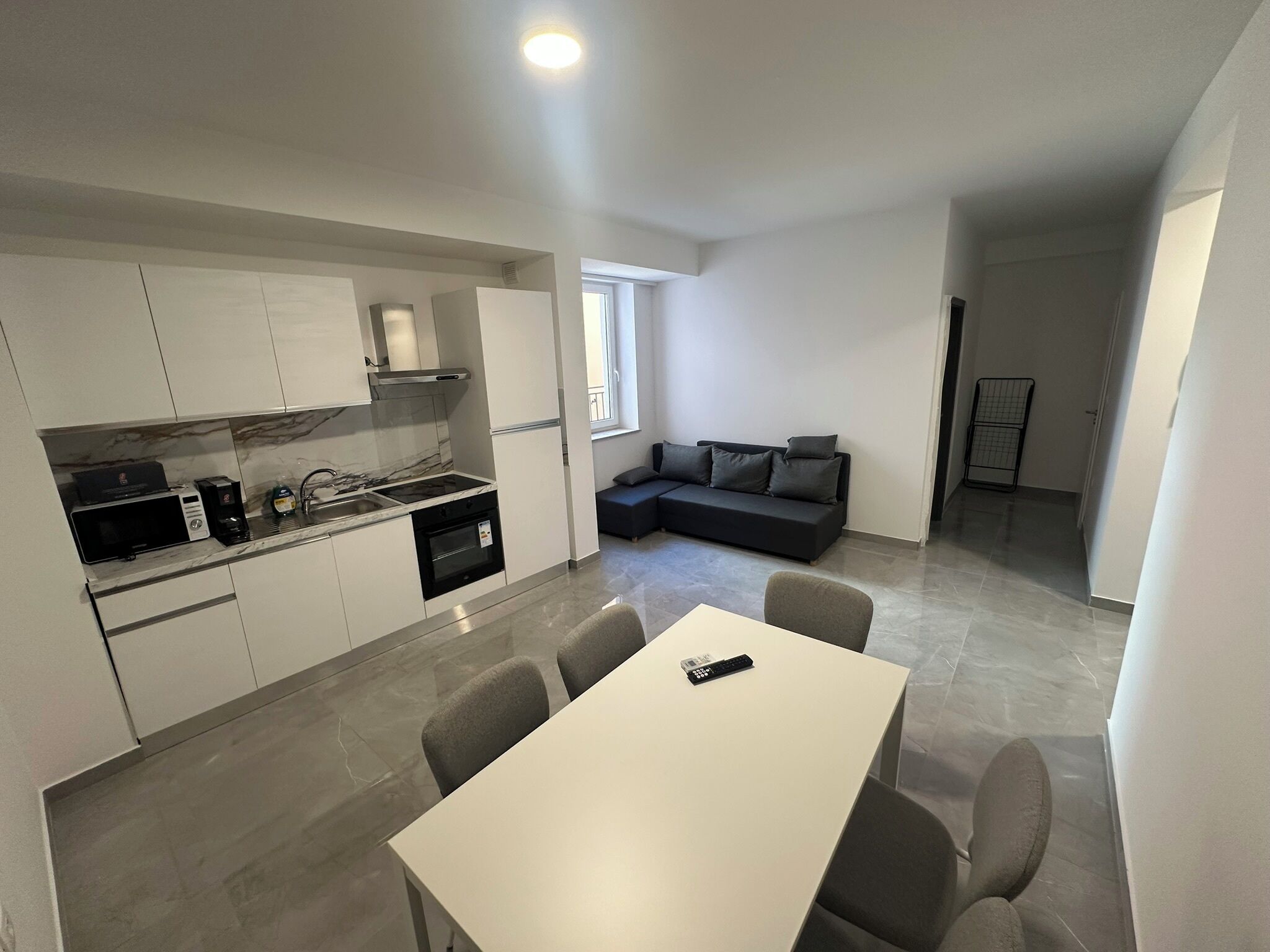 A modern kitchen with a dining area, a sofa, and a small table.
