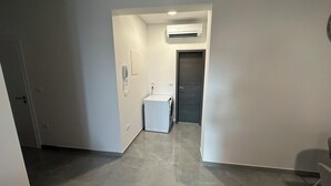 Un corridoio con una lavatrice, una porta e un condizionatore.