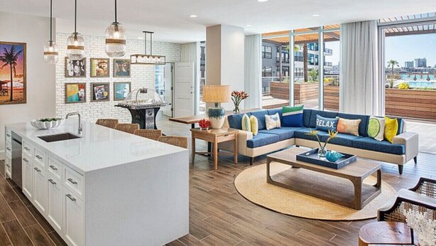 A modern living area with a kitchen, a blue sofa, and a large window offering a view of the city. - Margaritaville Vacation Club - Nashville, Studio Suite close to everything (Nashville)