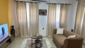 Una sala de estar con sofá, sillón, televisor y un jarrón decorativo.