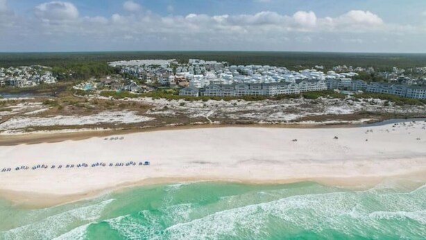 Ein Küstenresort mit Strandhäusern, einem Sandstrand und Wellen.