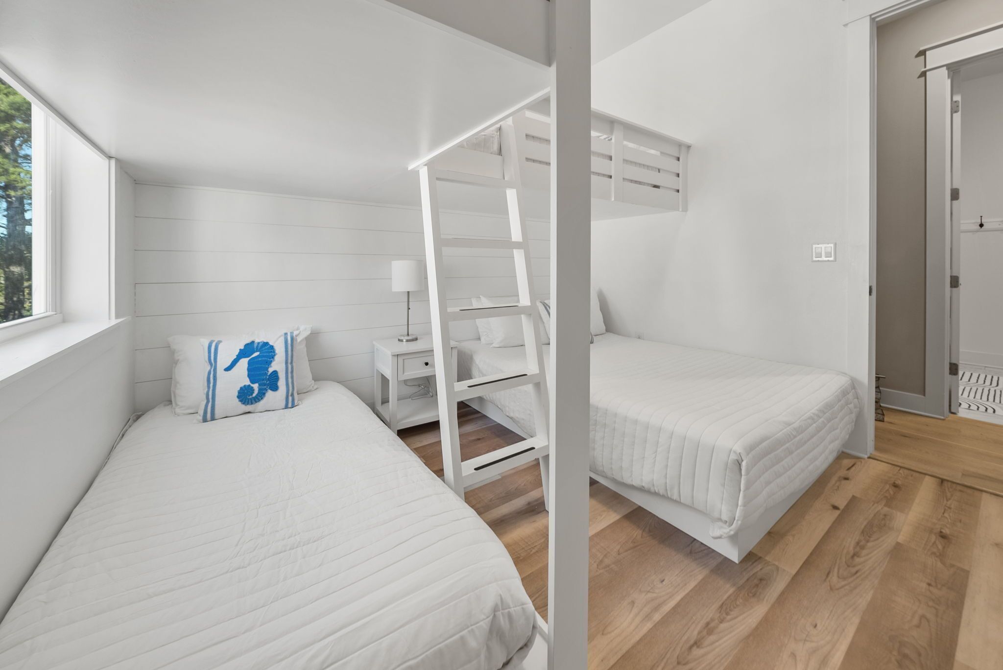 Un dormitorio con dos camas, una escalera, una mesita de noche y una ventana.