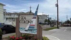 A sign for Sea Colony with a nautical theme, including a boat and waves.