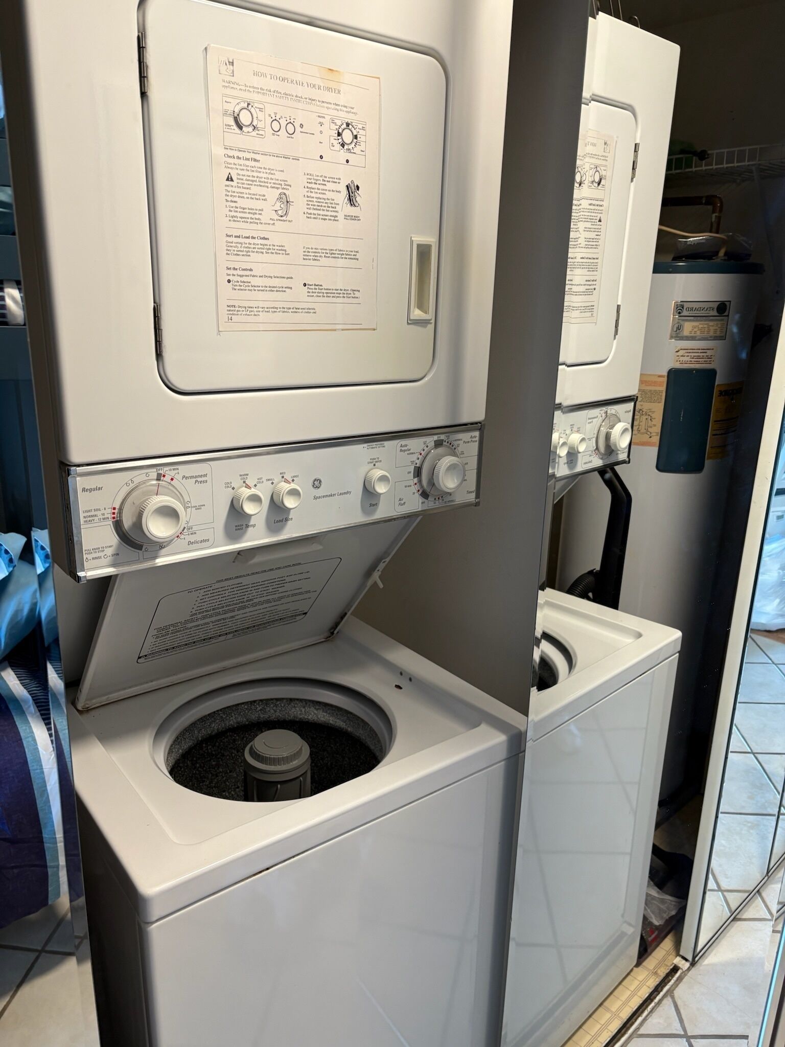 Vue de face d’un appareil combiné lave-linge et sèche-linge, avec les boutons de commande et le manuel d’utilisation.