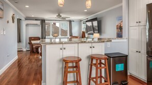 A modern kitchen with a central island, two bar stools, a refrigerator, and pendant lighting. - Hampton Beach, Free Parking, Sunsets (Hampton)