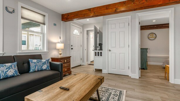 A modern living room with a dark sofa, wooden coffee table, and a wooden beam ceiling. - Hampton Beach, Free Parking, Sunsets (Hampton)