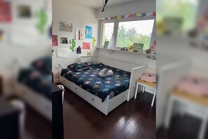 Une chambre à coucher comprenant un lit, une petite table de chevet, une fenêtre avec vue et des éléments décoratifs sur les murs.