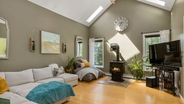 Una sala de estar acogedora con un sofá, una chimenea, un televisor y un ventanal grande.