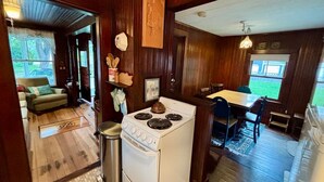 A compact kitchen with a stove, sink, and dining area. - Classic Rye Beach Cottage (Rye)