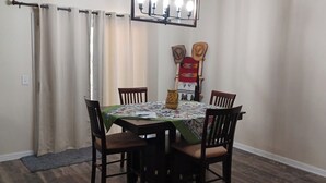 A dining area with a table set for four, surrounded by chairs, and a decorative wall piece above the table. - Charming 1-bedroom house in Riverside (Riverside)
