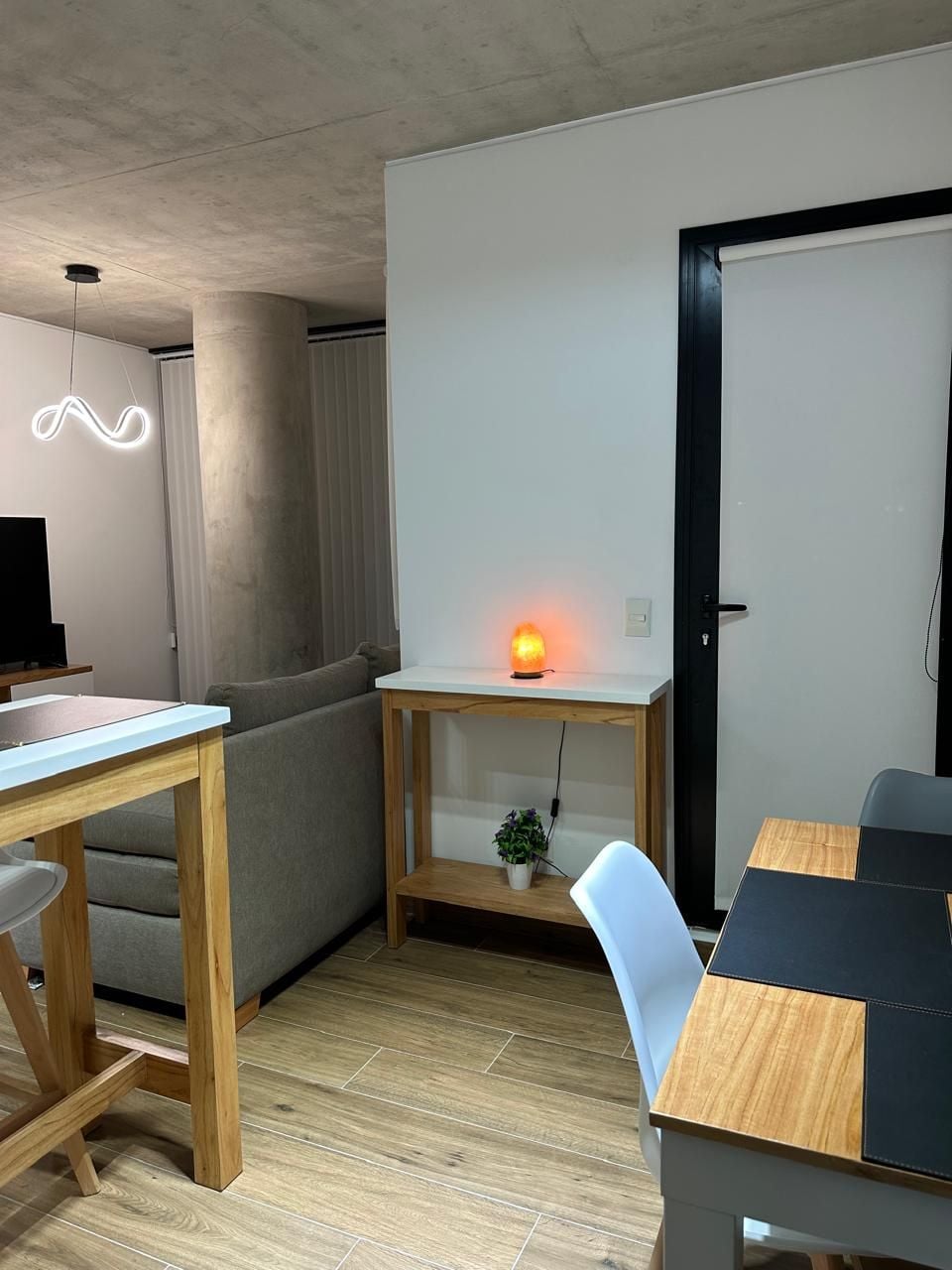 Un espacio de estar moderno con una mesa de comedor de madera, un sofá y un escritorio pequeño con un calentador.