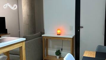 Un espacio de estar moderno con una mesa de comedor de madera, un sofá y un escritorio pequeño con un calentador.