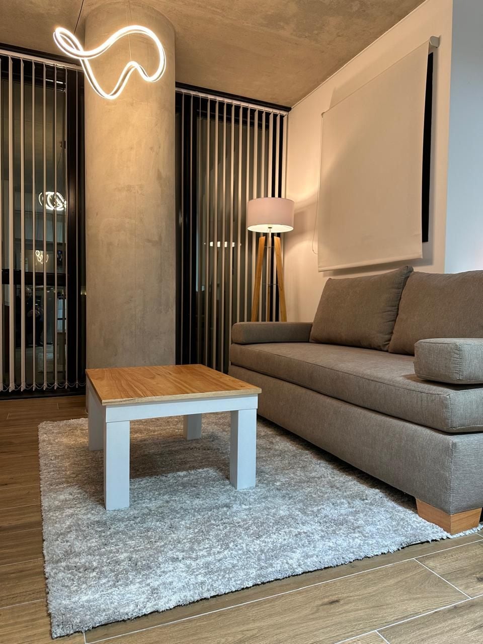 Un salon moderne avec un canapé, une table basse en bois et une lampe.