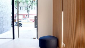 A modern interior with a seating area, a wooden panel wall, and a view of the street outside. - Hestia at Icon Boulevard Caseros (Buenos Aires)