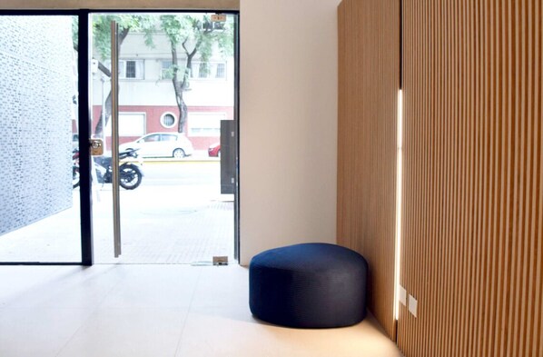 A modern interior with a seating area, a wooden panel wall, and a view of the street outside. - Hestia at Icon Boulevard Caseros (Buenos Aires)