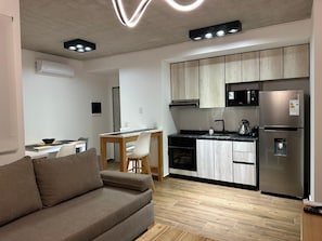 A modern kitchen with a refrigerator, microwave, and stove. There is a dining area with a table and chairs. - Hestia at Icon Boulevard Caseros (Buenos Aires)