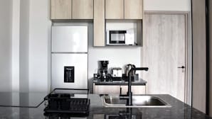 A modern kitchen with a black countertop, stainless steel sink, and wooden cabinets. - Hestia at Icon Boulevard Caseros (Buenos Aires)