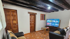 A living room with a television, two sofas, a small table, and a wooden door. - MEXICAN HOUSE WITH LOVE (San Sebastián del Oeste)