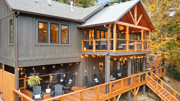 Une cabane à deux étages dotée d’une terrasse, de meubles d’extérieur et de guirlandes lumineuses.