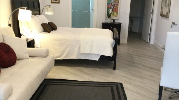 A hotel room with a bed, a sofa, a desk, and a ceiling fan.
