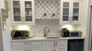 A modern kitchen with white cabinetry, a built-in microwave, a coffee maker, and a toaster.