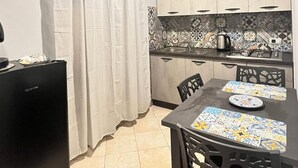 Une cuisine compacte avec un coin repas, comprenant un réfrigérateur, une cuisinière et une table avec des chaises.