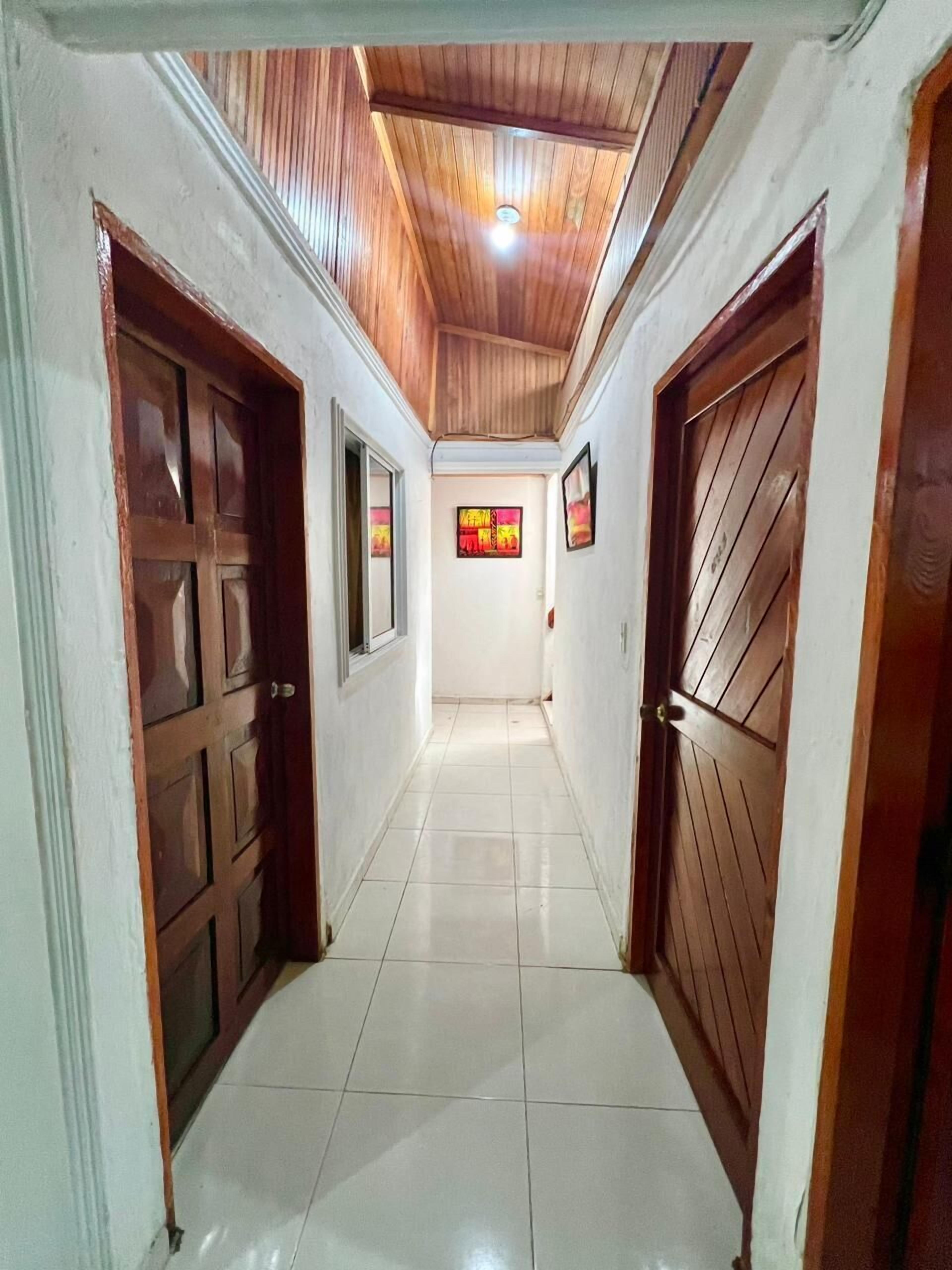 Un pasillo con puertas de madera y piso de baldosas.