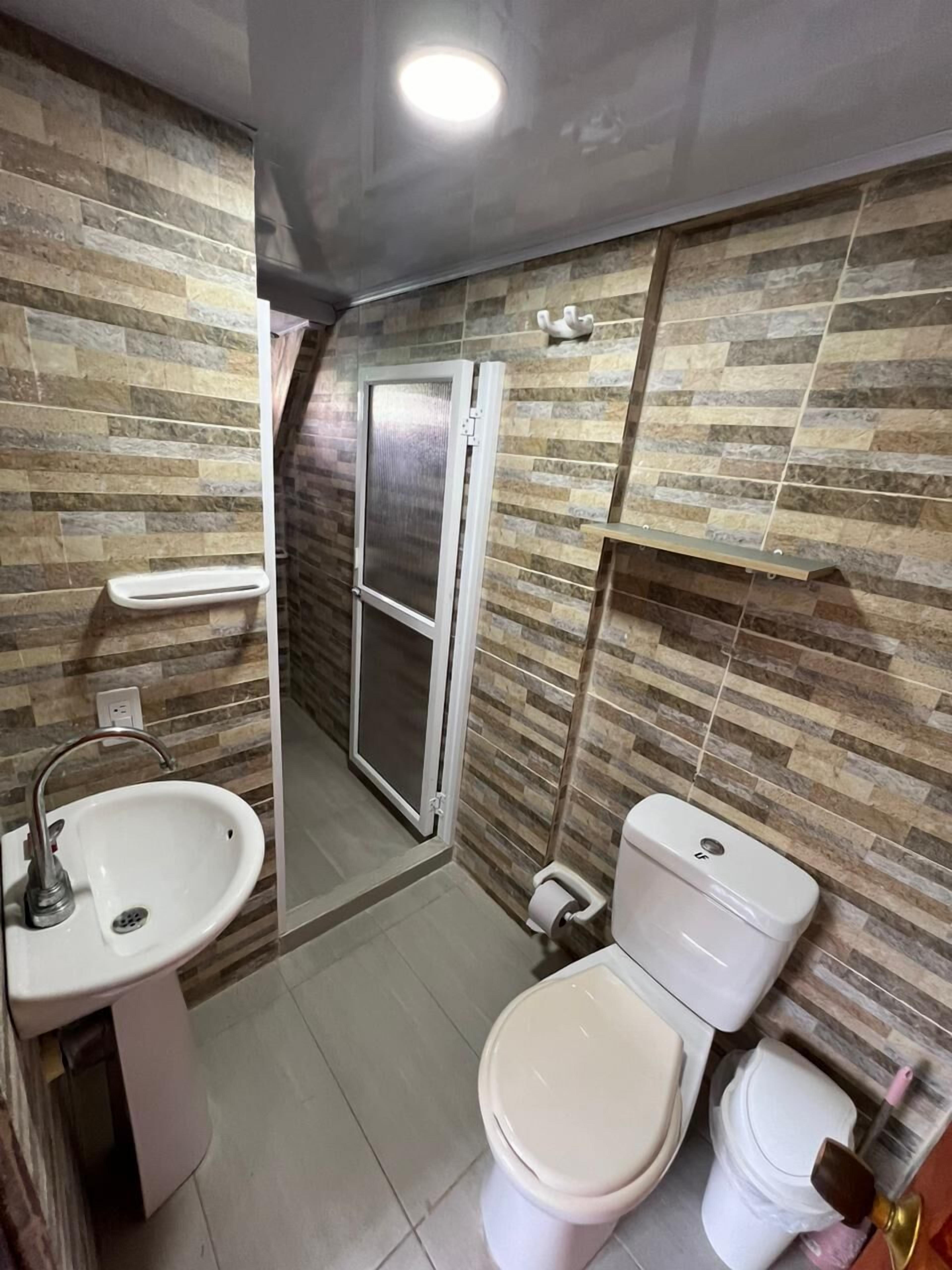 Et badeværelse med toilet, håndvask og brusebad.