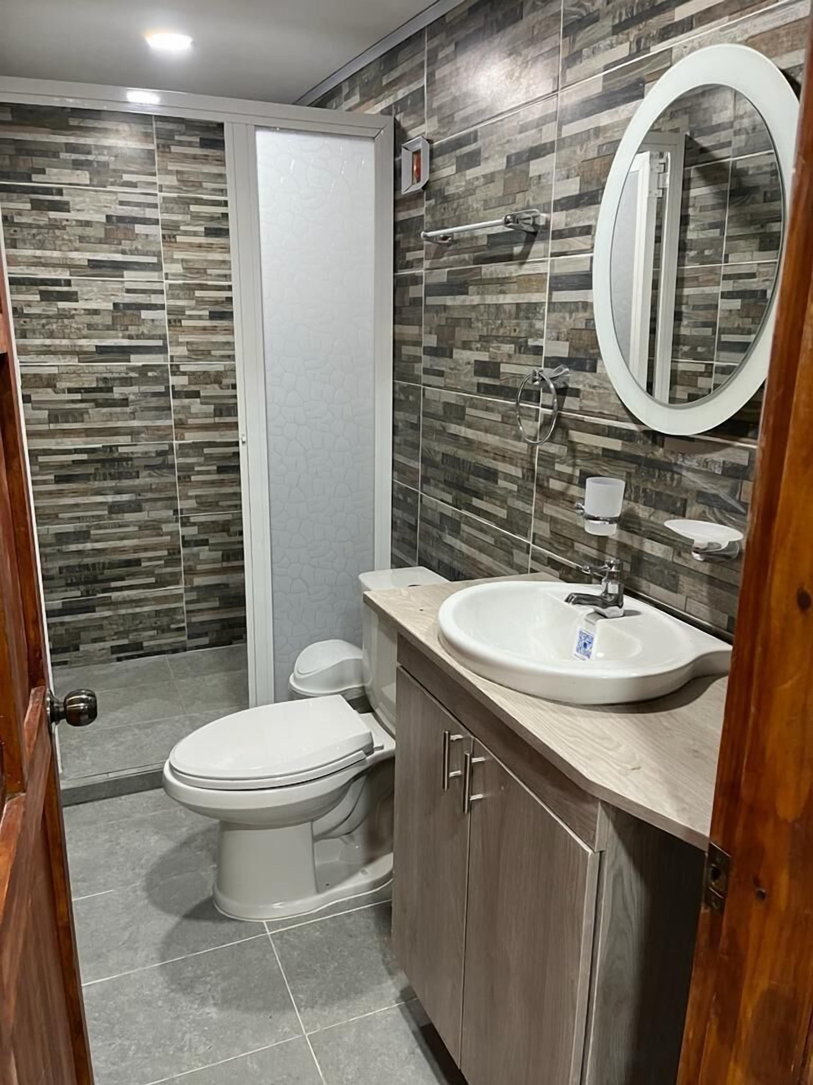 A modern bathroom with a toilet, sink, and mirror.