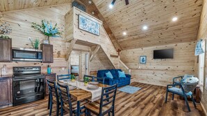 Een houten chalet van binnen, met een eethoek, keuken en woongedeelte.