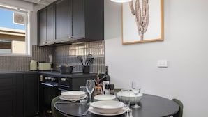A modern kitchen with dark cabinets, a round dining table, and a framed cactus artwork on the wall. - Enjoy a Luxurious Elwood Escape (Elwood)