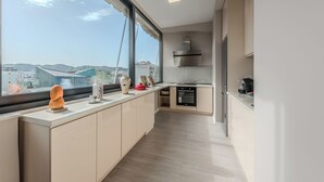 Una cocina moderna con un ventanal grande, horno empotrado y campana extractora de acero inoxidable.