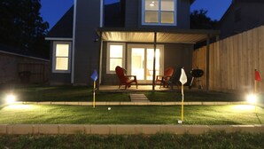 A backyard with a covered patio, a grill, and outdoor seating.