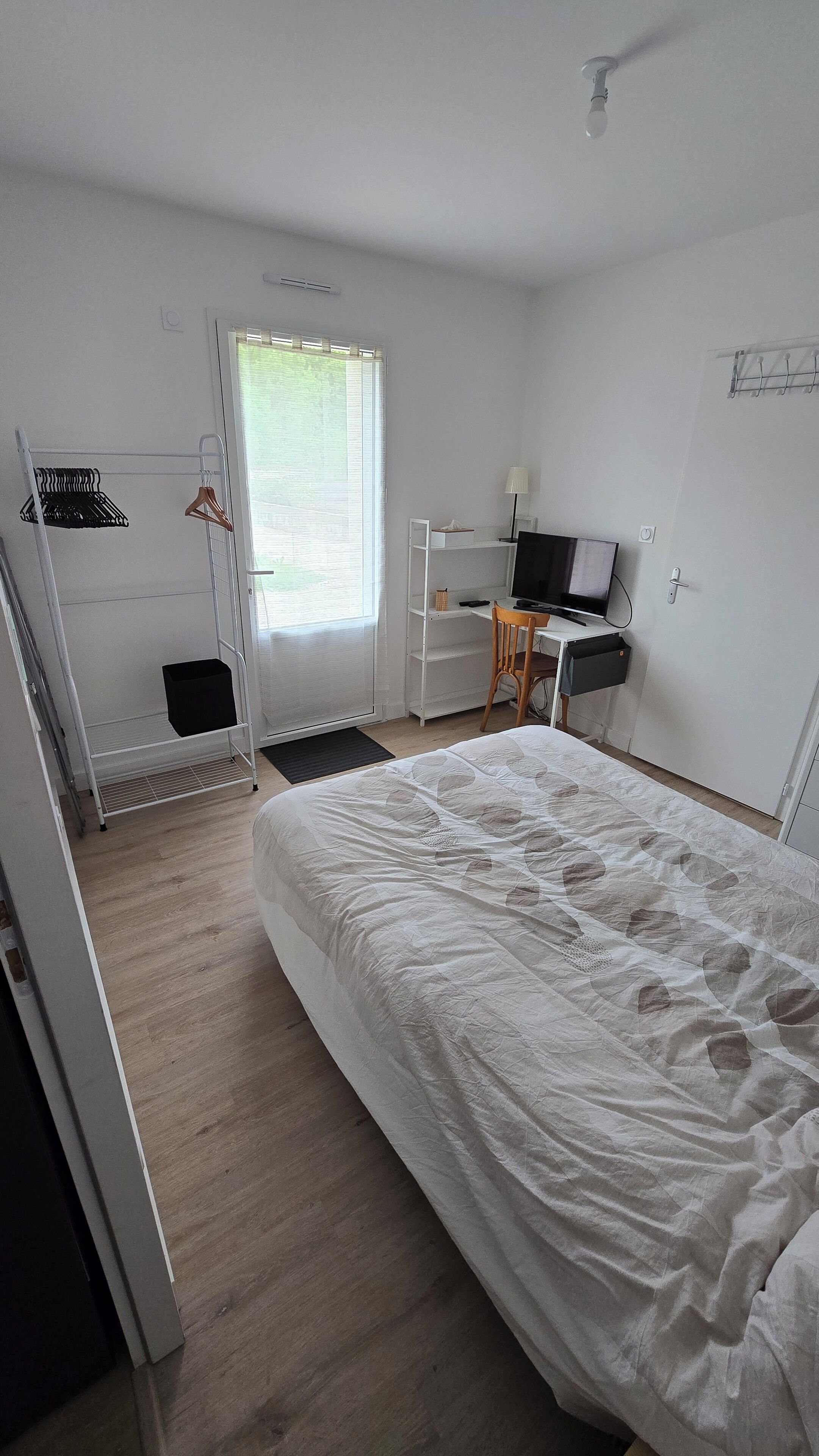 Une chambre à coucher avec un lit, un bureau, une chaise, un téléviseur et un radiateur.