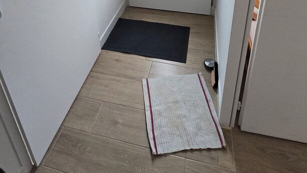 A narrow hallway with a door at the end, a black mat, and a small rug on the floor. - 2-bedroom self-contained apartment sleeps 4 to 6, 20min from beach (Curzon)