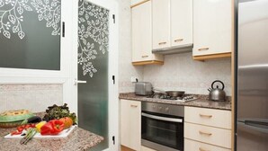 A kitchen with white cabinets, a stove, an oven, and a refrigerator.