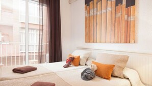 A hotel room with two beds, a large window with curtains, and a wall-mounted artwork.