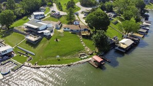 An aerial view of a lakeside property with a dock, grassy areas, and several buildings. - Freshly Renovated 4 BR Lake House, 2 Docks, Free Kayaks, 2 Fire Pits (Dry Ridge)