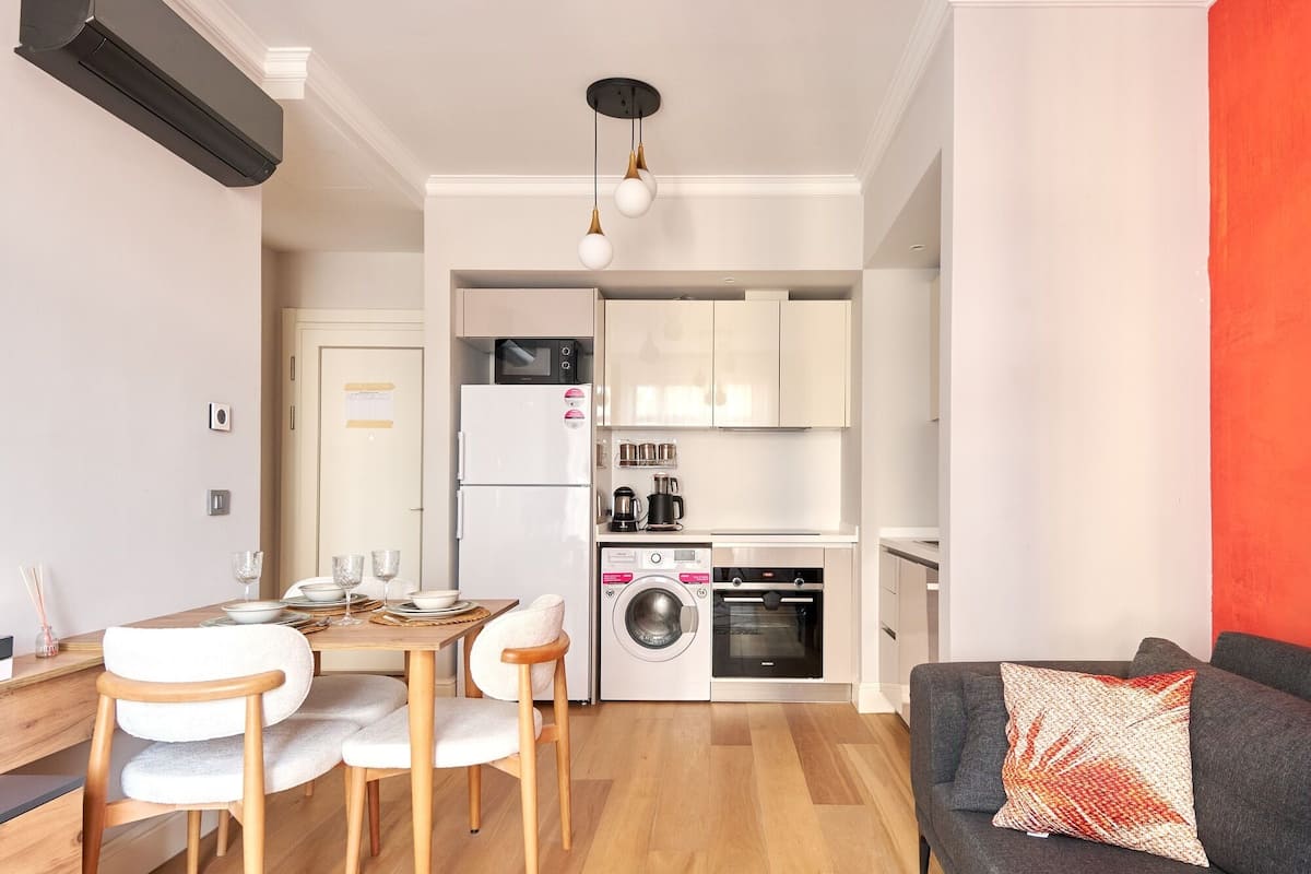 Un espacio habitable compacto con comedor, kitchenette y sofá.