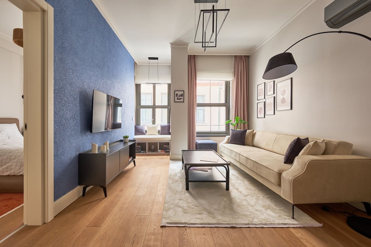 Una sala de estar moderna con un sofá, una mesa de centro, un televisor y una pared decorada en azul.