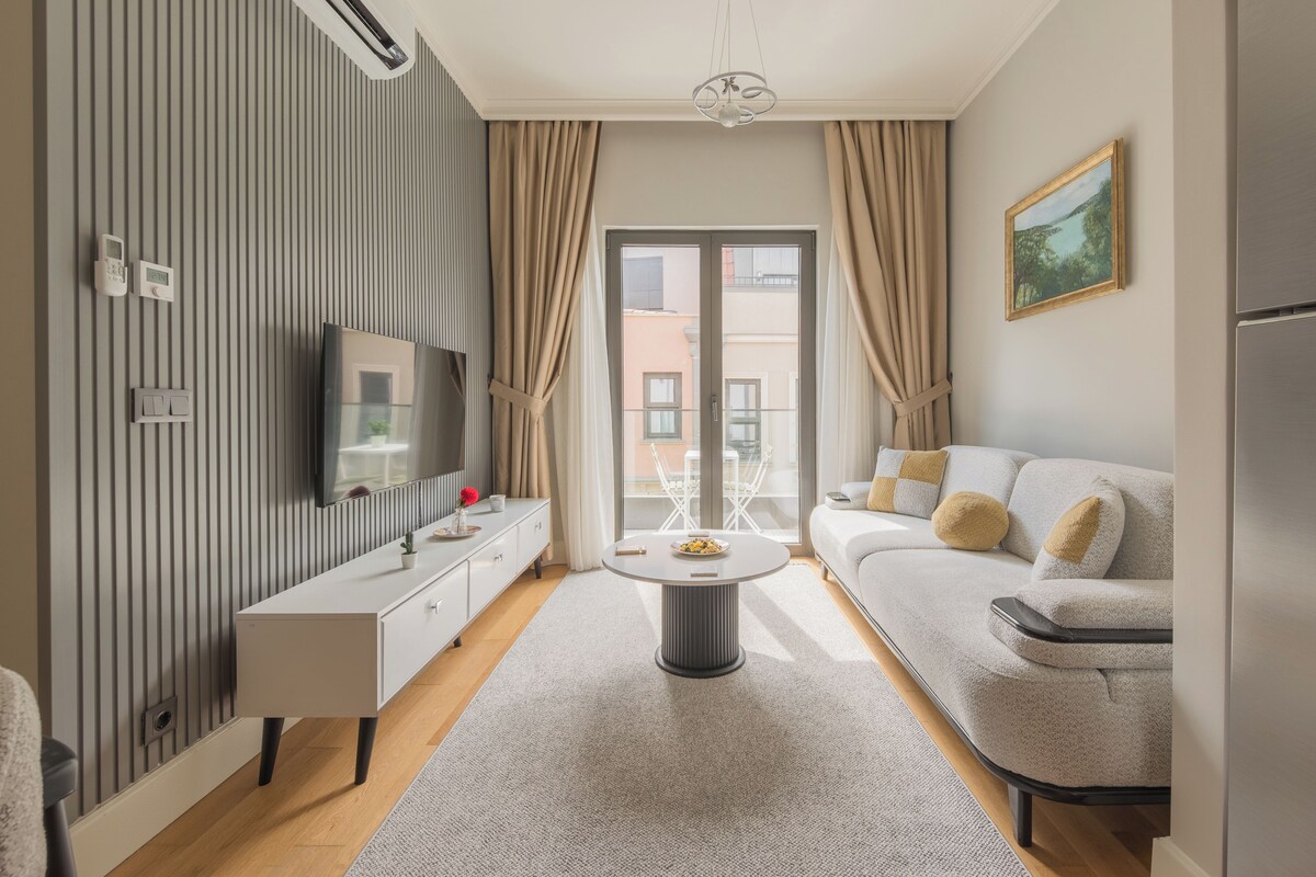 Un salon moderne avec un canapé, une table basse, un téléviseur et un balcon offrant une vue agréable.