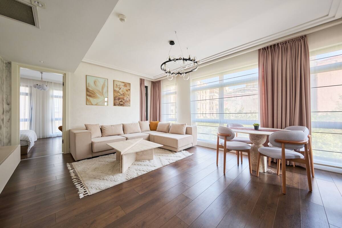 Una sala moderna con un sofá modular, una mesa de centro y un comedor con sillas.