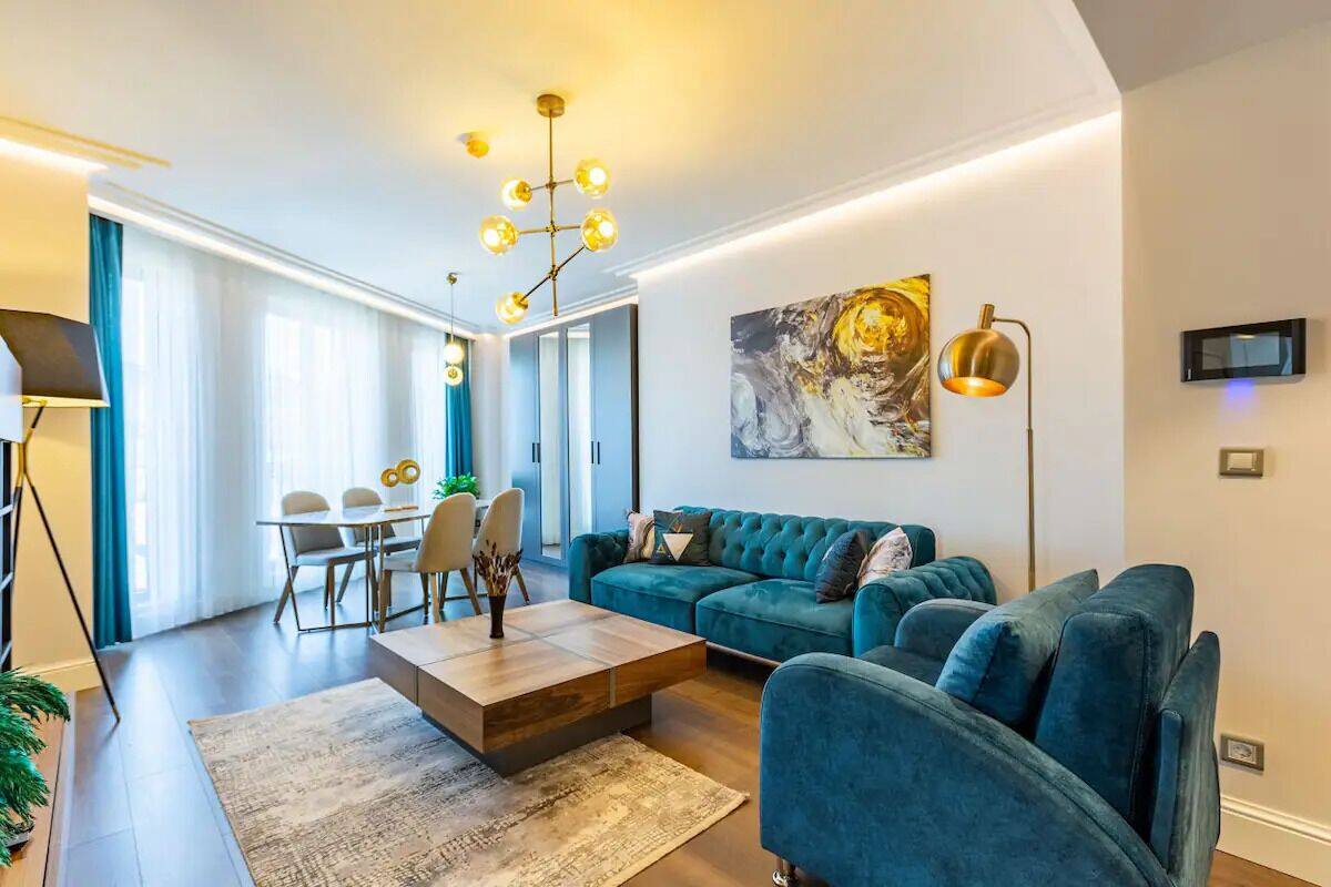 Una sala de estar moderna con un sofá color turquesa, una mesa de centro de madera y un comedor con una mesa y sillas.